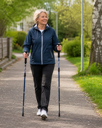 Kvinna promenerar i park med två stavar som ger stöd och bättre balans.